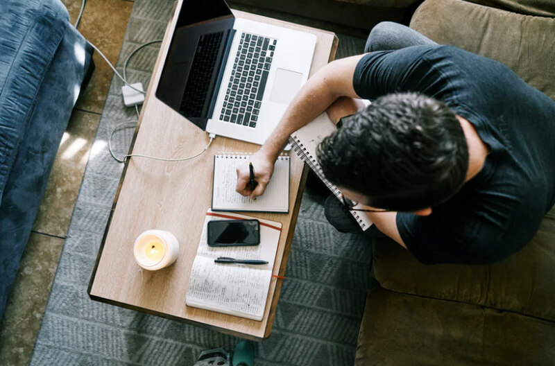 Man sitting on couch working on laptop